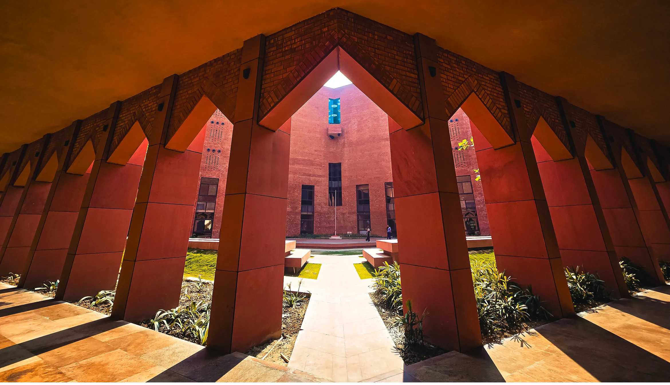 The Lucknow campus: a colonnade of red sandstone arches with pointed brick heads, looking through to a courtyard